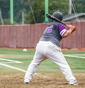Action shot of a baseball player preparing to swing during a game on a field.