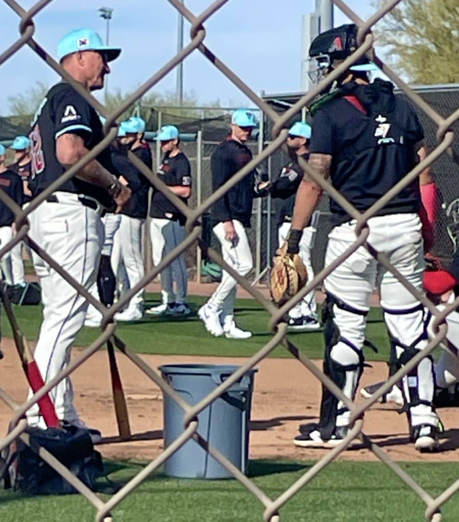 Arizona Diamondback coach and catcher talking. Fencing in the foreground
Salt River Fields